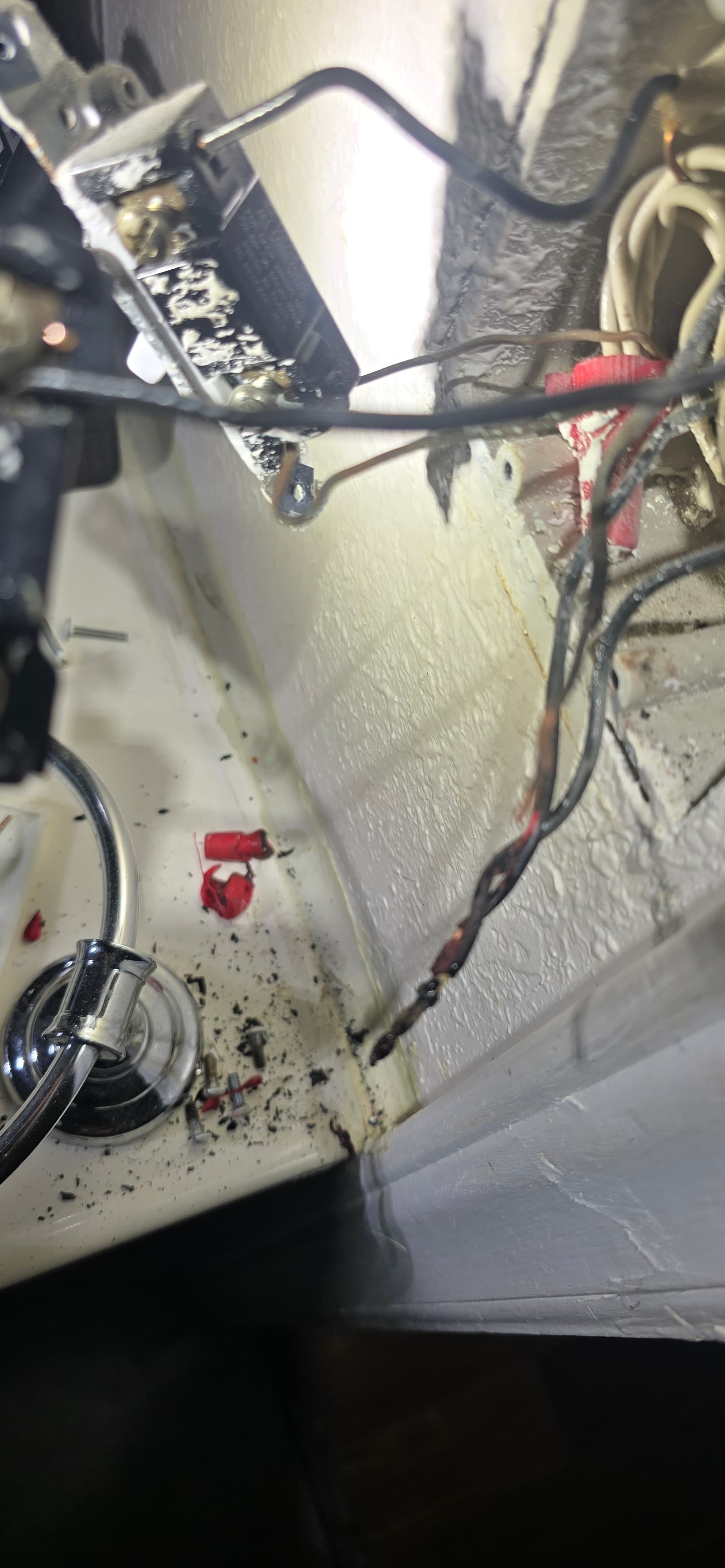 Severely burnt electrical wiring with melted insulation and black soot debris near a damaged outlet.