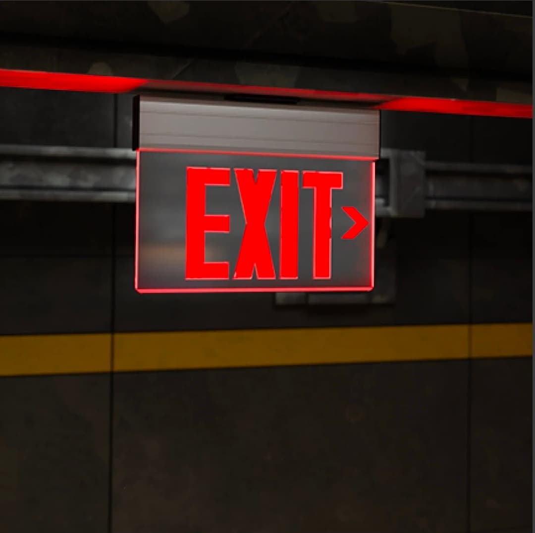 Illuminated red EXIT sign with a right arrow hanging from a dark, industrial ceiling.